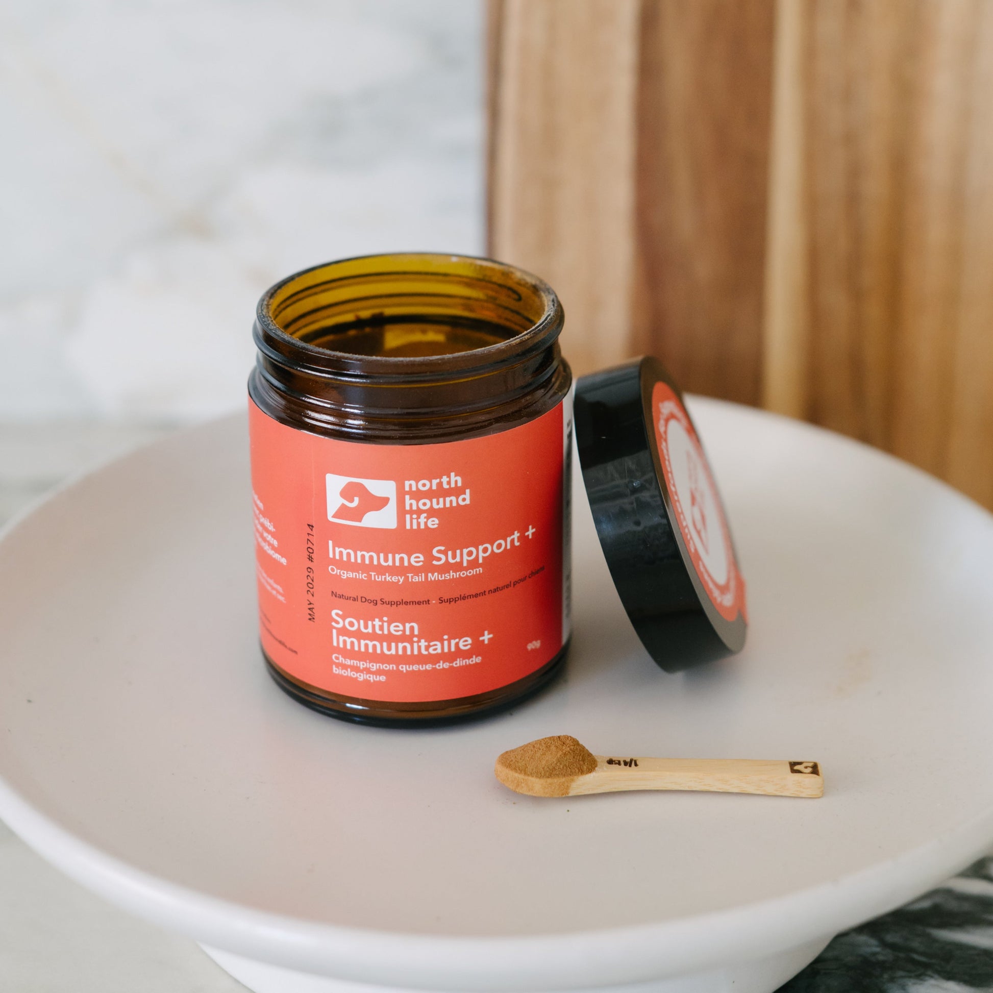 Jar of immune support supplement on a white plate with a wooden spoon